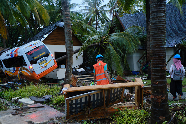 Les secouristes marchent le 23 décembre 2018 à Tanjung Lesung, en Indonésie, près d'un bus et d'un bungalow détruits par un tsunami et détruits par un tsunami. Plus de 220 personnes auraient été tuées après qu'un tsunami provoqué par un volcan ait frappé la côte autour du détroit de Sunda, en Indonésie, samedi soir, blessant plus de 600 personnes. (Photo : Ed Wray/Getty Images)