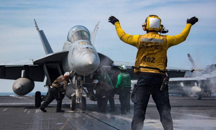 Un marin américain guide le pilote d'un avion à bord du porte-avions Carl Vinson dans l'ouest de l'océan Pacifique, le 2 mai 2017. (Sean M. Castellano/US Navy via Getty Images)