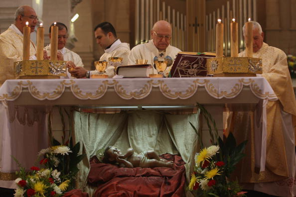 -Michel Sabbah, patriarche latin de Jérusalem, est entouré du clergé catholique alors qu'il se prépare à donner la communion sur le baigneur représentant l'enfant Jésus lors de la messe du jour de Noël à l'église Sainte-Catherine le 25 décembre 2007 à Bethléem en Cisjordanie. Un calme relatif dans la région a été reconnu pour attirer des dizaines de milliers de pèlerins et de touristes dans la ville biblique à l’occasion de Noël. Photo de David Silverman / Getty Images.