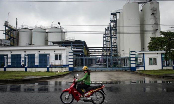 Une femme vietnamienne conduit une motocyclette devant une usine dans une zone industrielle de la ville centrale de Danang au Vietnam, le 10 novembre 2017. (Lillian Suwanrumpha / AFP / Getty Images)
