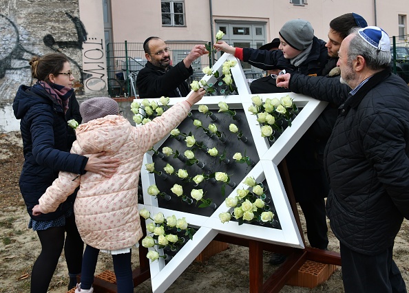 -Des enfants collent des roses blanches dans une sculpture en forme d’étoile de David sur le chantier de construction d'une nouvelle synagogue à Potsdam, dans l'est de l'Allemagne, le 9 novembre 2018, à l'occasion du 80e anniversaire du pogrom nazi de Kristallnacht. Photo BERND SETTNIK / AFP / Getty Images.