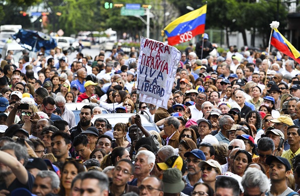 -Des activistes anti-gouvernementaux écoutent le président de l'Assemblée nationale du Venezuela, Juan Guaido, lors d'une réunion publique extraordinaire devant le siège du Programme des Nations Unies pour le développement (PNUD) à Caracas le 11 janvier 2019. Photo YURI CORTEZ / AFP / Getty Images.