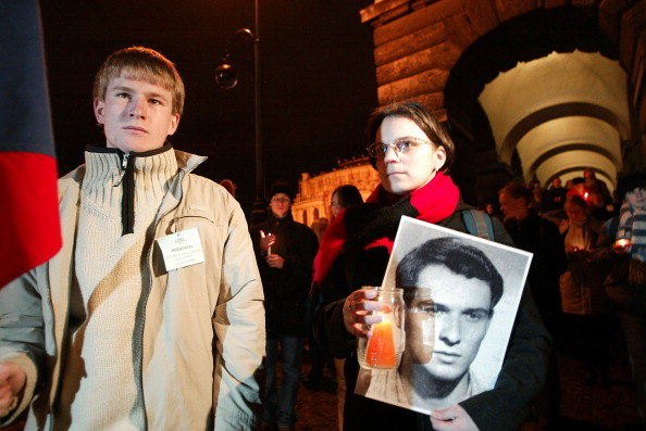 -Plus de 500 étudiants et professeurs de la Faculté des lettres et arts, allument des bougies, tenant un drapeau tchèque et des portraits de Jan Palach, et se rassemblent le 15 janvier 2004 sur la place Jan Palach à Prague pour commémorer le 35e anniversaire de son auto-immolation le 16 janvier 1969. Il protestait contre l’occupation soviétique. Photo DAVID NEFF / AFP / Getty Images.