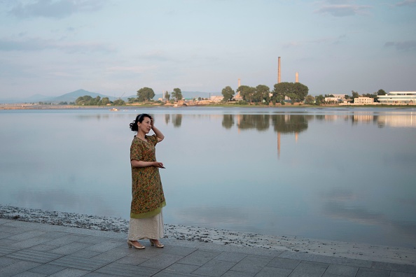 -Une femme chinoise se promène sur les rives de la ville frontalière chinoise de Dandong, dans la province du Liaoning (nord-est de la Chine), le 30 mai 2018. La ville de Dandong, principal point de passage entre la Corée du Nord et la Chine, espère avoir une nouvelle impulsion économique après que la résolution sur les armes nucléaires. Photo FRED DUFOUR / AFP / Getty Images.