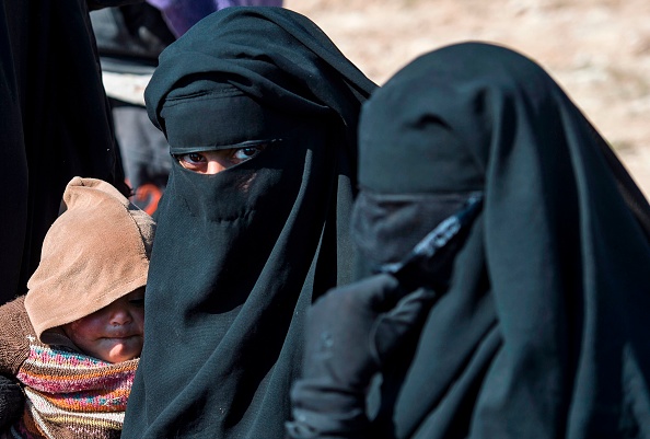 Plusieurs femmes de djihadistes accompagnées de leur progéniture fuient les combats qui ont lieu près de la ville de Baghouz, dans la province de Deir Ezzor, à l’est de la Syrie. Crédit : FADEL SENNA/AFP/Getty Images.