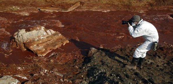 -Un photographe hongrois portant une tenue de protection prend des photos du ruisseau Torna dans le village de Kolontar le 14 octobre 2010. L'aide aux victimes d'un déversement de boue toxique qui a tué neuf personnes en Hongrie est venue de toutes les directions. Photo FERENC ISZA / AFP / Getty Images.