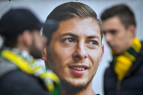 -Des supporters du FC Nantes aux côtés d'un portrait de l'attaquant argentin Emiliano Sala avant une séance d'entraînement en équipe au centre d'entraînement La Joneliere à La Chapelle-sur-Erdre, dans l'ouest de la France, le 24 janvier 2019, trois jours après la disparition de l'avion transportant Sala. Photo de LOIC VENANCE / AFP / Getty Images.