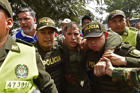 -Des policiers colombiens accompagnent un policier vénézuélien qui a déserté du Venezuela sur le pont international Simon Bolivar à Cucuta, en Colombie, après que le gouvernement du président Nicolas Maduro eut ordonné de fermer temporairement la frontière avec la Colombie le 23 février 2019. Photo LUIS ROBAYO / AFP / Getty Images.