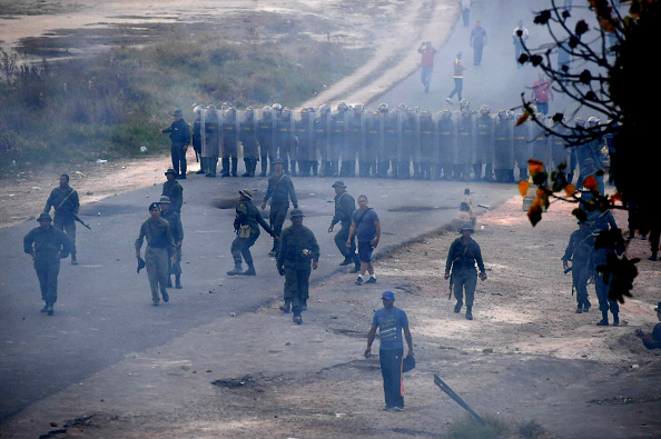 -La police anti-émeute fait le mur devant un poste de police vénézuélien à la frontière avec Pacaraima, dans l'État de Roraima, au Brésil, où des affrontements ont éclaté alors que des efforts étaient déployés pour amener de l'aide dans le pays frappé par la crise, le 23 février 2019. Les forces de sécurité du président Nicolas Maduro ont tiré sur des manifestants et des camions d'aide humanitaire ont été incendiés. Photo de Nelson Almeida / AFP / Getty Images.