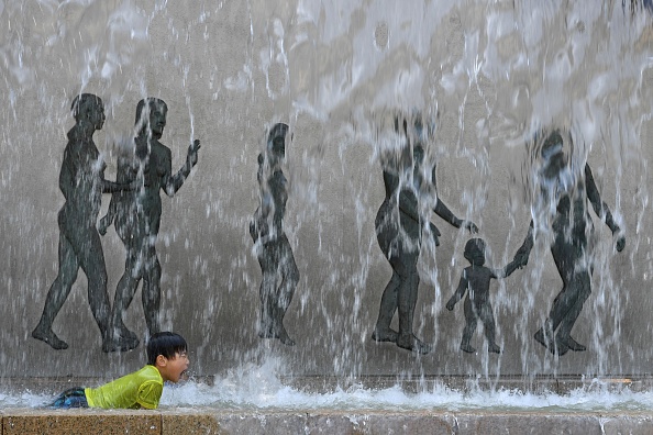 -Un enfant se rafraîchit dans une fontaine dans un parc de Tokyo le 9 juillet 2017. Photo TOSHIFUMI KITAMURA / AFP / Getty Images.