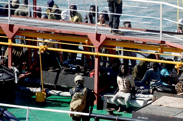 Malte : des policiers se tiennent devant des migrants à bord du Motor Tanker El Hiblu 1 qui a été détourné par des migrants dans le Grand Port de La Valette le 28 mars 2019, après que les forces armées maltaises ont pris le contrôle du navire.    (Photo : JONATHAN BORG/AFP/Getty Images)