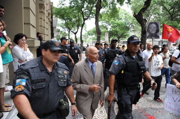 -Un vieil homme militaire à la retraite est escorté alors que des proches de personnes torturées et disparues crient des slogans lors d'une manifestation devant le club militaire de Rio de Janeiro, où l'armée célèbre le 48e anniversaire du coup d'Etat militaire de 1964, le 29 mars 2012. Photo ANTONIO SCORZA / AFP / Getty Images.