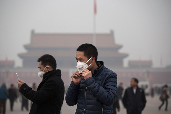 -Un touriste met un masque pour se protéger contre la pollution alors qu'il se rend sur la place Tiananmen pendant le smog sur la place Tiananmen à Beijing, en Chine. Photo par Kevin Frayer / Getty Images.