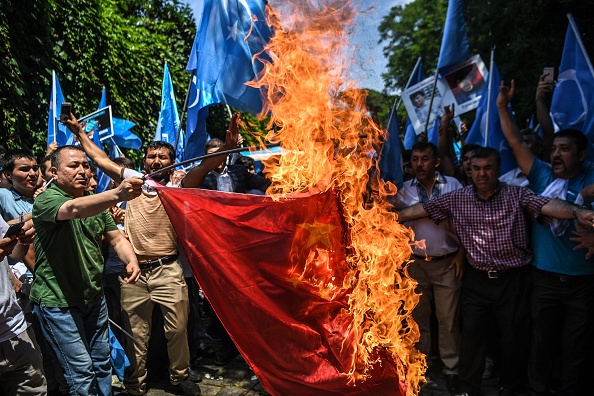 -Des partisans de la minorité ouïghoure à majorité musulmane et des nationalistes turcs brûlent un drapeau chinois lors d'une manifestation dénonçant le traitement réservé aux musulmans d'origine ethnique ouïghoure par la Chine lors d'une émeute meurtrière le 5 juillet 2018 à Urumqi, devant le consulat chinois à Istanbul. Photo par OZAN KOSE / AFP / Getty Images.