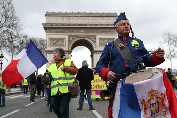 Un gilet jaune revêtu d’une tenue d’inspiration napoléonienne joue du tambour à quelques mètres de l’Arc de Triomphe pendant l’acte XVII, le 9 mars 2019. Crédit : KENZO TRIBOUILLARD/AFP/Getty Images.