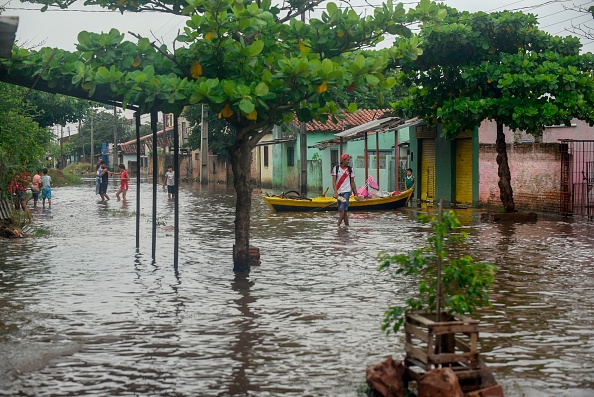 -Les gens marchent dans l'eau dans une zone inondée d'Asunción le 3 avril 2019 après le débordement de la rivière Paraguay en raison des fortes pluies des dernières semaines. Photo de Norberto DUARTE / AFP / Getty Images.