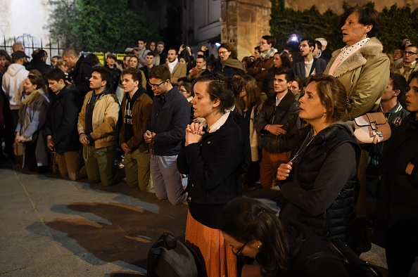 -Les gens se mettent à genoux sur le trottoir alors qu'ils prient les flammes engloutissent la cathédrale Notre-Dame de Paris le 15 avril 2019. Un incendie colossal a ravagé la célèbre cathédrale Notre-Dame du centre de Paris provoquant l'effondrement de la flèche. Photo par ERIC FEFERBERG / AFP / Getty Images.