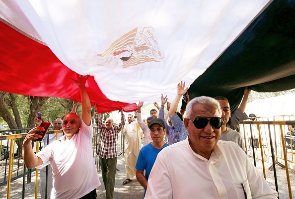 -Des ressortissants égyptiens vivant au Koweït passent sous le drapeau national de leur pays alors qu'ils se préparent à voter lors d'un référendum sur des amendements constitutionnels à l'ambassade d'Egypte à Koweït le 19 avril 2019. Photo de Yasser Al-Zayyat / AFP / Getty Images.