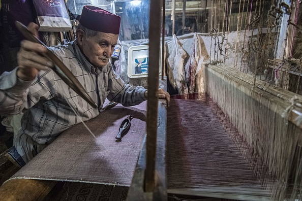 -Abdelkader Ouazzani, le dernier maître tisserand du brocart marocain, travaille sur une tapisserie dans son atelier de la vieille ville de Fès le 10 avril 2019. Ses mains habiles créent des tissus de soie chatoyants, rehaussés de fils d'or ou d'argent, pour les bijoux de mariée ou pour les créations de designer ou de mobilier haut de gamme. Photo de FADEL SENNA / AFP / Getty Images.