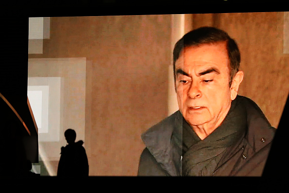 -Les piétons passent devant un grand écran montrant des images de l'ancien président de Nissan Motor Co., Carlos Ghosn, dans un programme d'informations le 4 avril 2019 à Tokyo, au Japon. Photo de Takashi Aoyama / Getty Images.