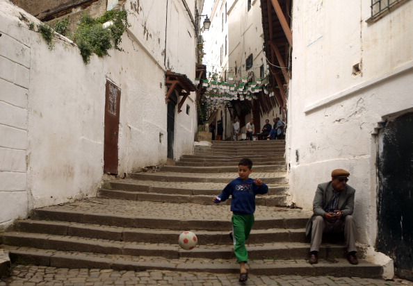 -Un garçon passe avec un ballon devant un Algérien assis dans l'escalier dans la vieille ville d'Alger, connue sous le nom de « Kasbah », le 16 avril 2014. Photo PATRICK BAZ / AFP / Getty Images.