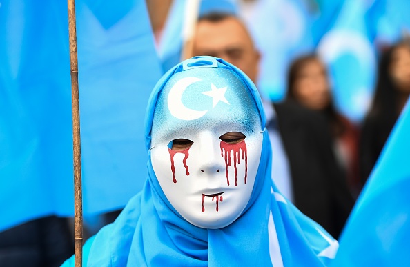 Un masque blanc avec des larmes de sang. Marche de protestation de l'ethnie ouïghour demandant à l'Union européenne d'appeler la Chine à respecter les droits de l'homme dans la région chinoise du Xinjiang et  la fermeture d'un "centre de rééducation" où des Ouïghours sont détenus. (Photo : EMMANUEL DUNAND / AFP / Getty Images.)