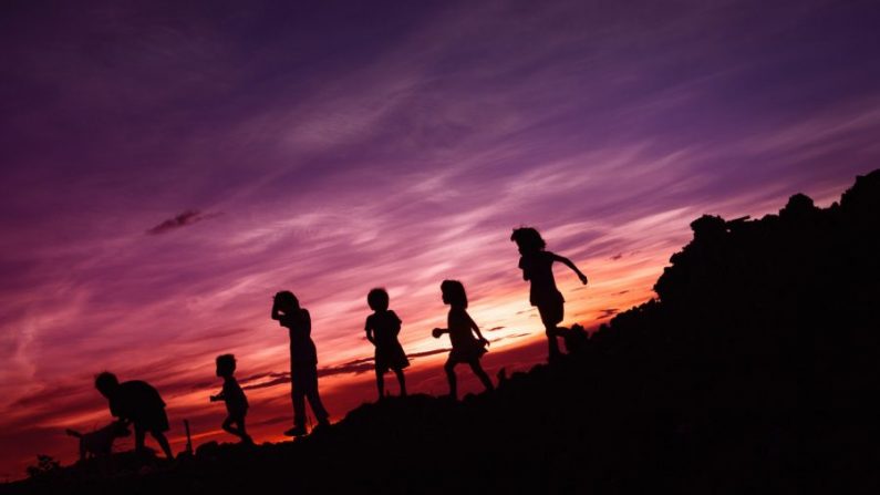 Des enfants jouant avec leur chien au coucher du soleil. (René Bernal/Unsplash)