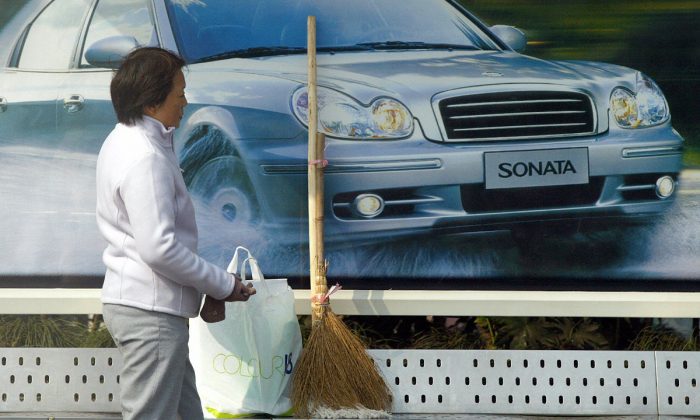 Une femme se tient devant une publicité de voiture. (Liu Jin/AFP/Getty Images)

