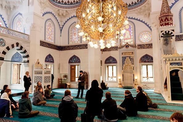 -Un employé de la mosquée parle aux visiteurs de la mosquée Sehitlik lors d'une journée portes ouvertes des mosquées de Berlin, une journée de d'unité allemande le 3 octobre 2018 à Berlin, en Allemagne. La mosquée Sehitlik fait partie des mosquées les plus ornées de Berlin et sert principalement des musulmans de langue turque. Photo de Carsten Koall / Getty Images.