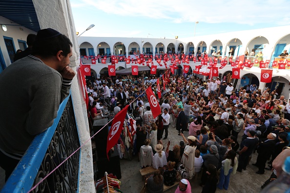 -Des pèlerins juifs prennent part à la procession de la "Ménara", une pyramide hexagonale représentant les cinq livres du prophète Moïse, à l'extérieur de la synagogue Ghriba sur l'île touristique de Djerba, le 23 mai 2019. Photo par FATHI NASRI / AFP / Getty Images.