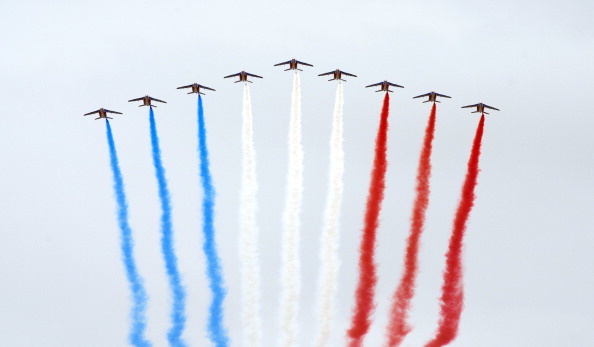 -La Patrouille de France, neuf avions Alpha de l'armée de l'air française relâchent des traînées de fumée bleue, blanche et rouge, aux couleurs du drapeau national français, survolent Paris lors du défilé militaire annuel du 14 juillet, le 14 juillet 2014, à l'occasion d’une invitation sans précédent aux 72 pays impliqués dans la Première Guerre mondiale à prendre part à son défilé militaire annuel du 14 juillet. Photo à ALAIN JOCARD / AFP / Getty Images.