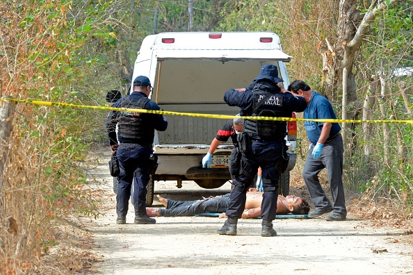 -Des experts légistes, des enquêteurs du parquet et des policiers travaillent sur les lieux du crime à côté du cadavre d'un homme dans la banlieue d'Acapulco, dans l'État de Guerrero, au Mexique, le 19 avril 2019. La violence à Mexico, qui est assiégée par des cartels de drogue assoiffés de sang qui engagent également du vol de carburant, de l’extorsion de fonds et des enlèvements. Photo de FRANCISCO ROBLES / AFP / Getty Images.