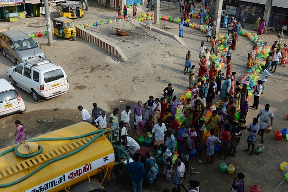 -Des résidents indiens font la queue avec des contenants en  plastique pour obtenir de l'eau potable auprès d'un camion-citerne de distribution situé dans la banlieue de Chennai le 29 mai 2019. Photo de ARUN SANKAR / AFP/ Getty Images.