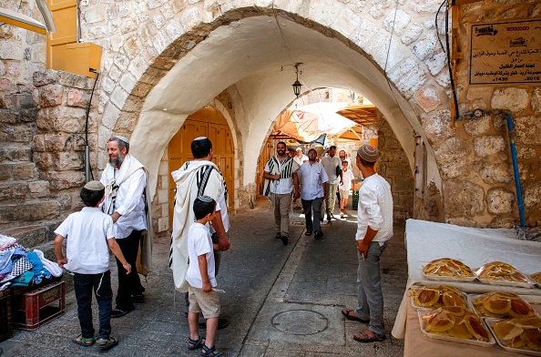 -Des colons juifs passent devant les étals et les magasins de vendeurs palestiniens alors qu'ils visitent le côté palestinien du marché de la vieille ville de Hébron en Cisjordanie, pendant le mois de jeûne sacré musulman du Ramadan, le 1er juin 2019. Photo de HAZEM BADER / AFP / Getty Images.