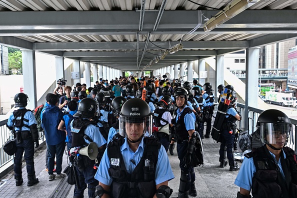 -La police monte la garde sur une passerelle près du siège du gouvernement au lendemain d'une violente manifestation contre la proposition controversée de loi sur l'extradition à Hong Kong le 13 juin 2019. Les marchés asiatiques s'effondrent à nouveau le 13 juin. Photo par Anthony WALLACE / AFP / Getty Images.