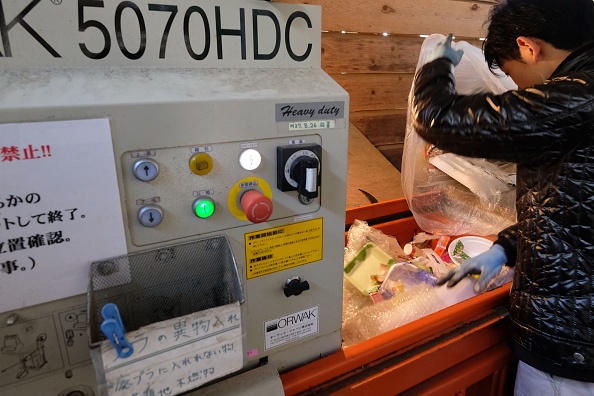 -Cette photo prise le 14 mars 2019 montre Kazuyuki Kiyohara, directeur d'un centre de traitement des déchets, en train de placer des déchets plastiques dans une machine de compactage située dans la ville de Kamikatsu, dans la préfecture de Tokushima. Les habitants font face à 45 catégories différentes pour leurs ordures alors que la ville vise à être « zéro déchet » d'ici 2020. Photo de KAZUHIRO NOGI / AFP / Getty Images.