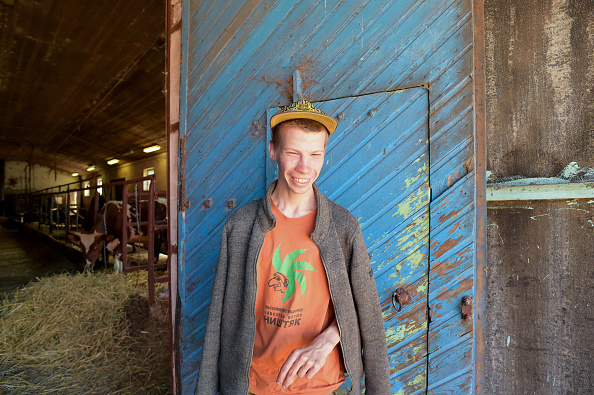 -Tolik, 21 ans, pose devant une étable à la ferme de Svetlana, à 130 km de Saint-Pétersbourg, le 18 mai 2019. À Svetlana, 18 Russes présentant divers types de troubles d'apprentissage, notamment Le syndrome de Down mène une vie de plein air à la ferme, avec l'aide de cinq enseignants et de trois bénévoles. Photo par Olga MALTSEVA / AFP / Getty Images.