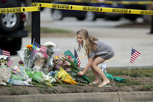 Une jeune fille laisse des fleurs sur un mémorial de fortune situé en dehors du lieu du crime au centre municipal de Virginia Beach le 1er juin 2019 à Virginia Beach, en Virginie. (Photo : Chip Somodevilla/Getty Images)