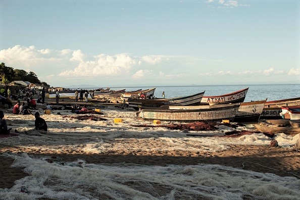 -Des pêcheurs malawiens réparent leurs filets de pêche, des bateaux de pêche attendent sur les rives du lac Malawi dans le village de Senga le 19 mai 2019 à Senga, au Malawi. Le lac Malawi est le troisième plus grand bassin d'eau douce d'Afrique. Photo de GIANLUIGI GUERCIA / AFP / Getty Images.