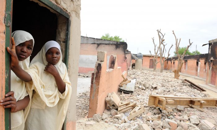 Une étudiante et une enseignante devant une infirmerie, une école primaire et un collège réduits en cendres  à Maidugri, au Nord Est du Nigéria. (Pius Utomi Ekpei/AFP/GettyImages)