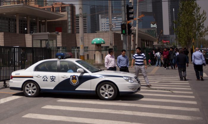 Voiture de police chinoise devant la foule. (Ed Jones/AFP/GettyImages)