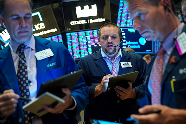 Les traders et les professionnels de la finance travaillent à la Bourse de New York (NYSE) à la cloche d'ouverture du 13 août 2019 à New York. L'indice Dow Jones Industrial Average a grimpé de 400 points en début de séance mardi, suivi par Apple après que l'administration Trump ait annoncé qu'elle retarderait les tarifs sur certains articles, qui devaient initialement entrer en vigueur le 1er septembre, jusqu'au 15 décembre. (Photo :  Drew Angerer/Getty Images)