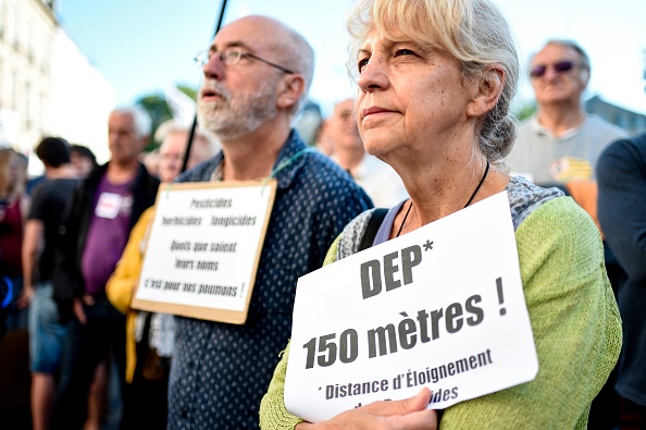 Des habitants brandissent une pancarte portant la mention " DEP (distance des pesticides) 150 mètres ", lors d'une manifestation de soutien au maire de Langouet Daniel Cueff, poursuivi pour avoir interdit les pesticides près des maisons de sa commune par un décret municipal, devant le tribunal administratif de Rennes, le 22 août 2019. (Photo : SEBASTIEN SALOM-GOMIS/AFP/Getty Images)