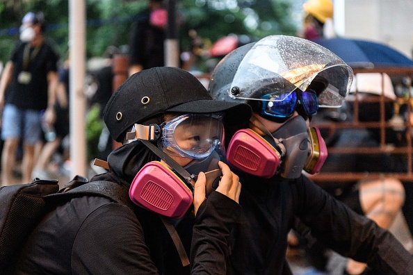 -Le 25 août 2019, Abby (à gauche), 19 ans, et son petit ami, Nick, 20 ans, attendent que la police lance des gaz lacrymogènes alors qu'ils assistent à une manifestation à Tsuen Wan, un quartier des nouveaux territoires de Hong Kong. Un masque à gaz ajusté avec amour, une main serrée avant de s'approcher des lignes de police et une agitation frénétique à travers des tourbillons de gaz lacrymogène. La relation d'Abby et Nick s'est épanouie sur les barricades pendant le long été de protestation de Hong Kong. Photo par Anthony WALLACE / AFP / Getty Images.