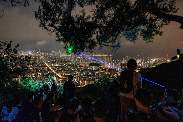 Des partisans de la démocratie agitent des pointeurs laser, des téléphones portables et des lanternes alors qu'ils se rassemblent au Lion Rock lors du festival de la mi-automne le 14 septembre 2019 à Hong Kong. (Photo :  Anthony Kwan/Getty Images)