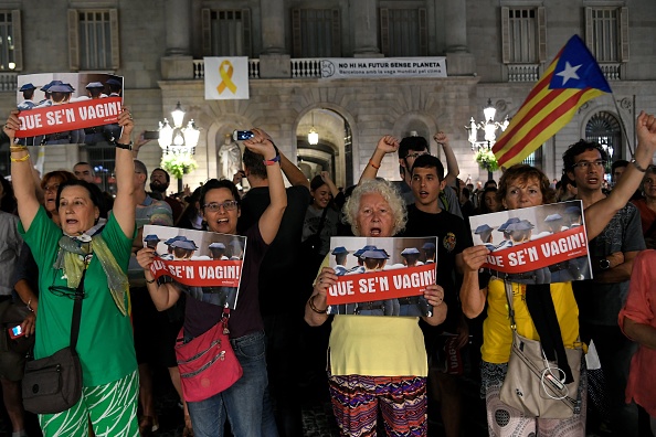 Des gens tiennent une pancarte indiquant «partons» et représentent des membres de la garde civile espagnole lors d'une manifestation devant le palais de la Generalitat sur la place Sant Jaume à Barcelone le 26 septembre 2019 pour protester contre la détention de sept militants radicaux pour appartenance présumée à à une organisation terroriste. (Photo : LLUIS GENE/AFP/Getty Images)