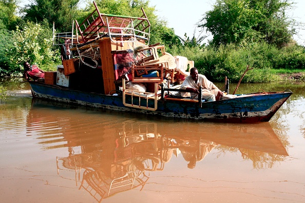 -Des hommes soudanais transportent leurs biens sur un bateau lors d'inondations soudaines dans le village de Wad Ramli, sur les rives orientales du Nil, à 50 km au nord de Kharoum, le 26 août 2019. Photo par EBRAHIM HAMID / AFP via Getty Images.