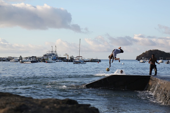 -Un jeune plonge dans la mer sur l'île française d'outre-mer de Mayotte, dans l'océan Indien, le 29 septembre 2019. Les fortes marées, récurrentes à Mayotte, mettent en évidence la vulnérabilité de ce territoire de l'océan Indien, menacé comme toutes les îles par réchauffement climatique, mais qui a la particularité de s’effondrer avec la naissance d’un volcan sous-marin. Photo par ALI AL-DAHER / AFP via Getty Images.