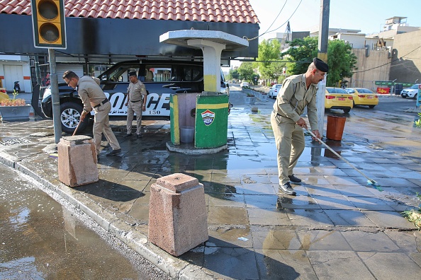 -Les forces de sécurité irakiennes nettoient une rue du 5 octobre 2019 dans le district de Karrada, dans la capitale irakienne, après la levée du couvre-feu qui a suivi une journée de violentes manifestations. Photo de SABAH ARAR / AFP / Getty Images.