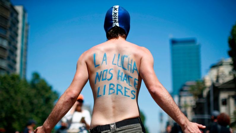 Un manifestant avec le slogan communiste "La lutte nous rend libres" défile à Santiago le 23 octobre 2019, le sixième jour consécutif de violence dans la rue au Chili. (PABLO VERA/AFP via Getty Images)